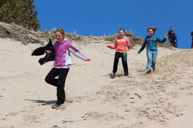 Children run down sand dune at Miniwanca
