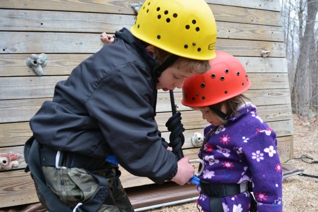 Brother helps sister prepare to climb tower at Camp Merrowvista